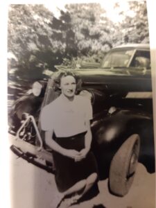 old photo of a woman standing by a car
